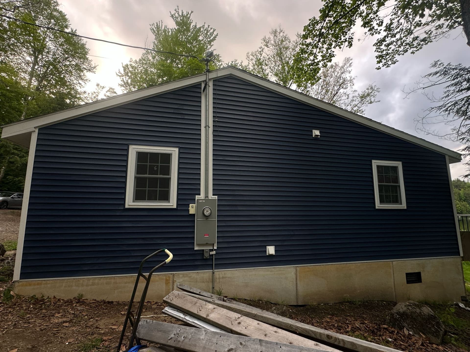 Navy blue siding side angle on lakefront cottage by Wolf's Siding, MA
