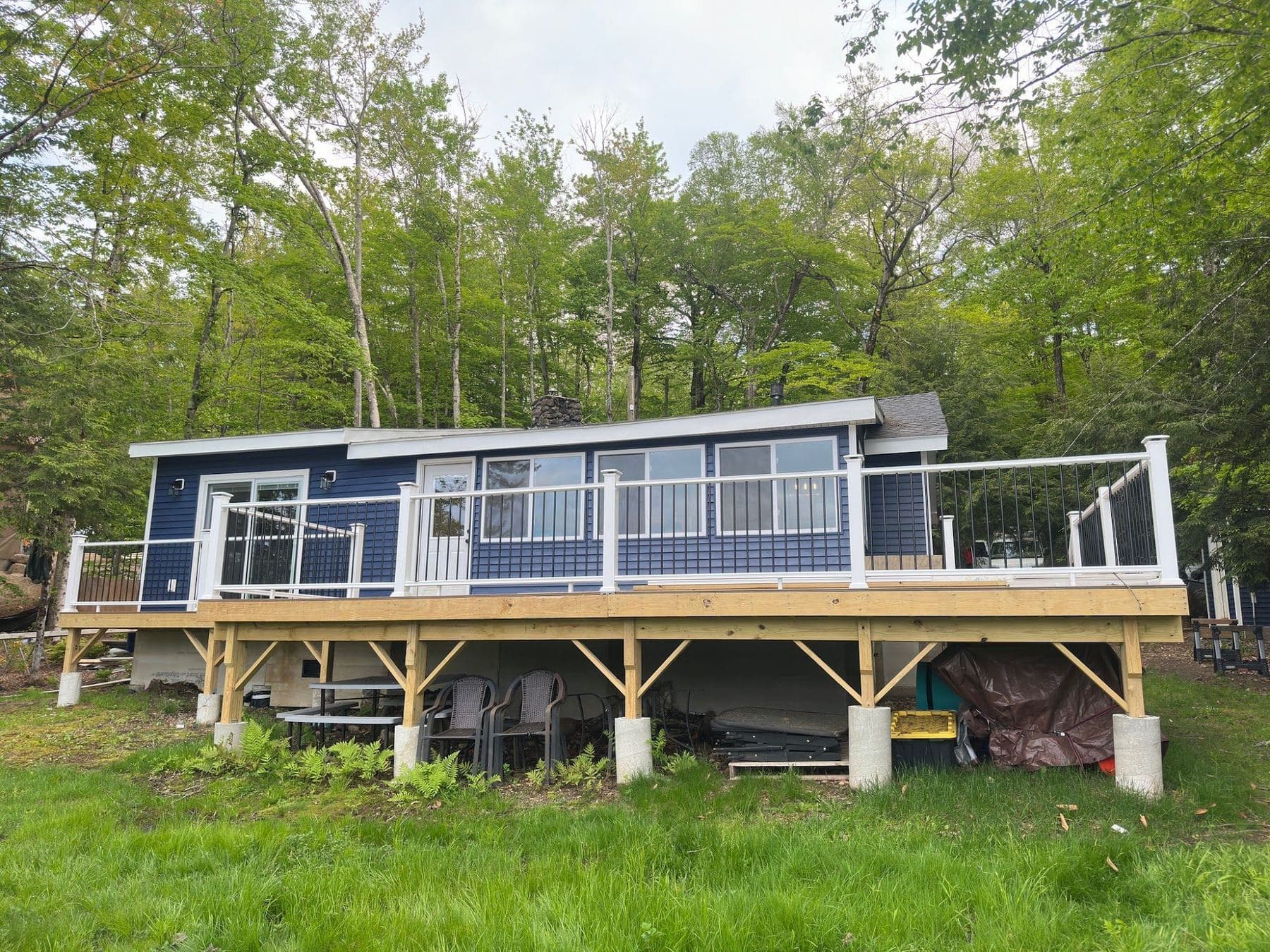 Navy lakeside cottage with a long deck and white railings in Stoddard, NH