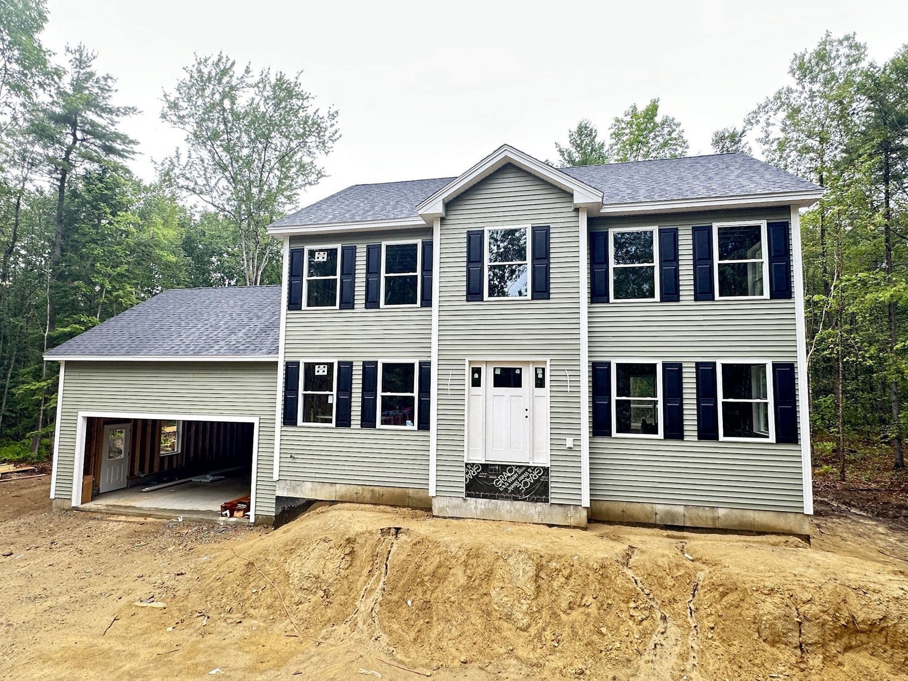 Sage green colonial with black shutters and an attached garage in New Durham, NH