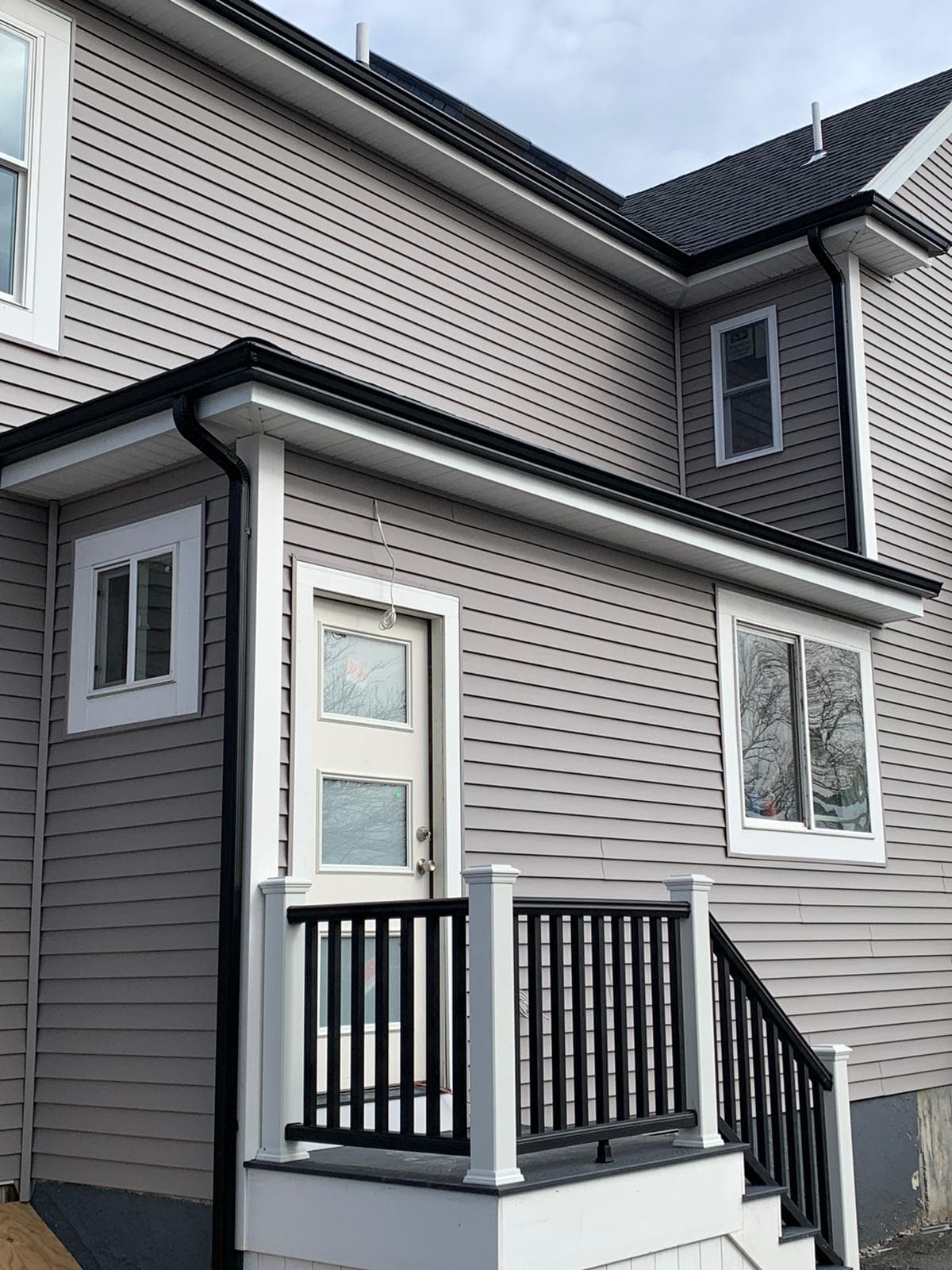 Black seamless gutters on gray siding home by Wolf's Siding, MA